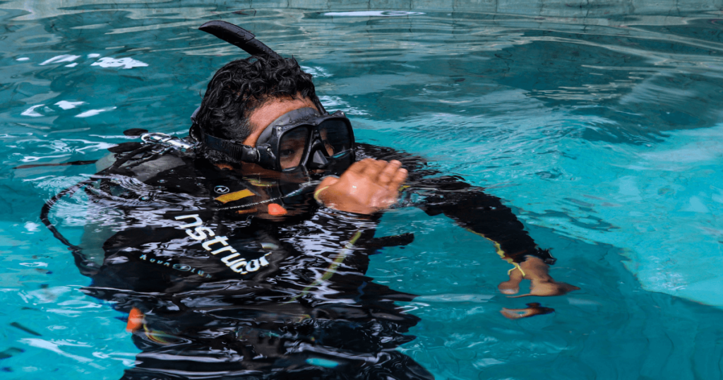 A scuba diver doing a weight check with their gear in a pool