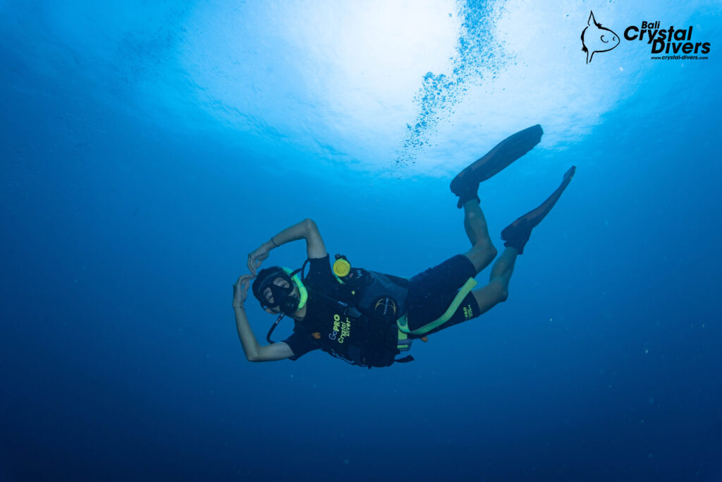 Scuba diver with full scuba gear in the ocean shown with alternate air source octopus on the left side of the diver